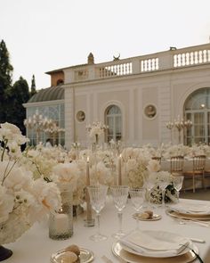 the table is set with white flowers and place settings