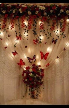 a vase filled with flowers and butterflies on top of a table next to a curtain