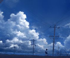 a person standing on the side of a road under power lines with clouds in the background