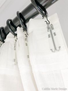 black and white curtains are hanging on the rod in front of a curtain with metal clips