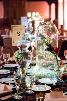 the table is set with plates, silverware and vases