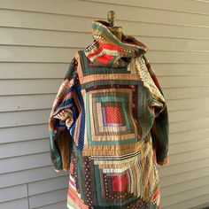 a dress made out of old quilts sitting on top of a wooden table next to a house