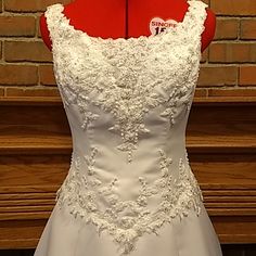 a white wedding dress on display in front of a brick wall