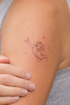 a woman's arm with a tattoo on it that has a small cupid angel flying through the sky