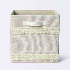 a white and beige storage box with a ribbon on the top, in front of a white background