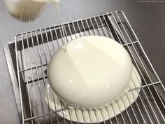 a white cake sitting on top of a metal rack next to a bottle of milk