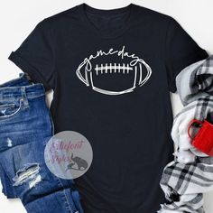 We know that the spirit of gameday begins with your outfit! Make sure you're ready for the season with our trendy gameday shirts. The perfect shirts for Football season or any gameday! These shirts are soft and lightweight - great to wear every day. Stylish enough to dress up or down! Black Tops For Game Day, Black T-shirt For Game Day In Fall, Black T-shirt For Fall Game Day, Sporty T-shirt For Game Day During Football Season, Black Tops For Game Day During Football Season, Varsity Tops With Team Name For Game Day, Game Day Varsity Pre-shrunk Top, Casual Team-colored Tops For Game Day, Casual Letter Print T-shirt For Tailgating