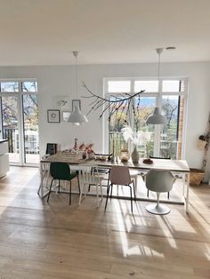 a dining room table and chairs in front of large windows with lots of natural light