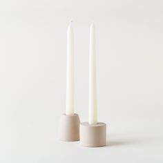 two white candles sitting next to each other