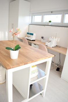 a wooden table topped with a potted plant next to a sewing machine and desk