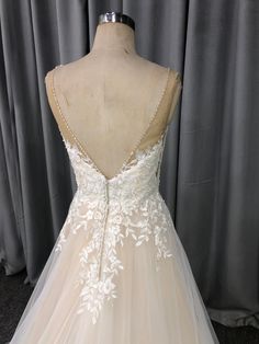 the back of a wedding dress with white flowers on it, and beaded detailing