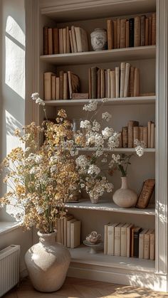 a vase filled with flowers sitting on top of a book shelf