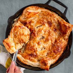 a skillet with some food in it and someone holding a spatula to eat