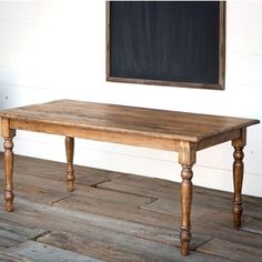 an old wooden table sitting in front of a chalkboard on the wall behind it