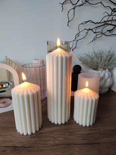 three white candles sitting on top of a wooden table