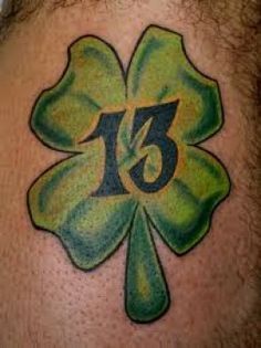 a man with a shamrock tattoo on his back has the number thirteen in it's center