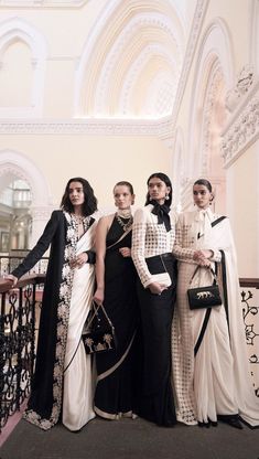 four women standing next to each other in long dresses