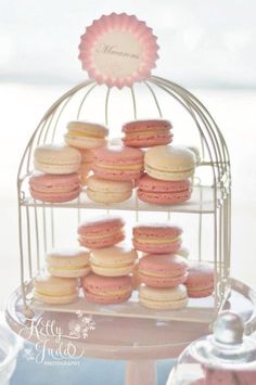 there are many pink and white macaroons on the cake stand