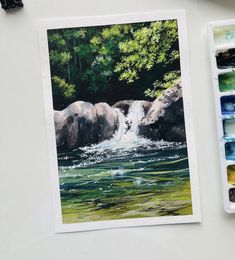 a watercolor painting of a waterfall with rocks and trees in the background, surrounded by paintbrushes