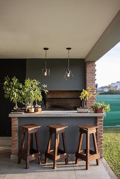 an outdoor kitchen with two stools next to the bar and potted plants on the counter