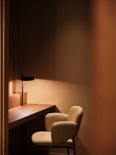 a chair sitting in front of a wooden desk with a lamp on top of it