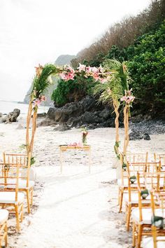 an outdoor ceremony set up with wooden chairs and flowers on the aisle at the beach