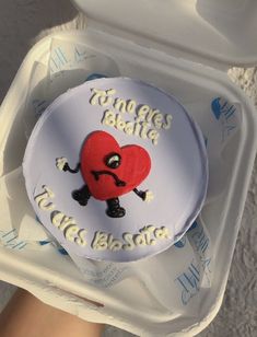 a heart shaped cake sitting on top of a plastic container in someone's hand