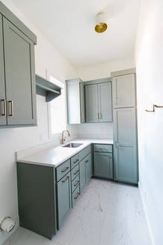 an empty kitchen with marble counter tops and gray cupboards on either side of the sink