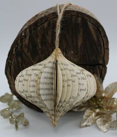 an ornament made out of book pages sitting on top of a piece of wood