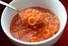 a white bowl filled with macaroni and cheese soup on top of a red place mat