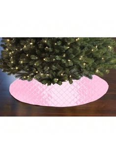 a small christmas tree in a pink pot on a wooden table with lights around it