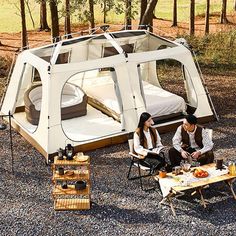 two people sitting in chairs near a tent with a bed on the ground next to it