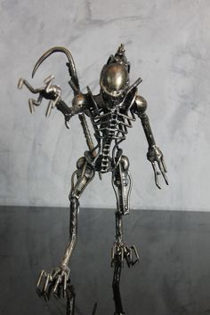 a metal figurine that looks like a robot with two hands on it's hips