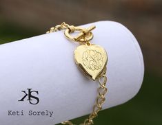 "Heart locket bracelet with engraved monogram. Bracelet will be featured with large link chain and toggle clasp. Add your message, date or inspirational word on the back of the locket for additional cost. Locket opens and holds 2 photos inside. Designs by Keti Sorely. Available Metal - Brass with 24K Yellow Gold Overlay - Brass with 14K Rose Gold Overlay - 14K Yellow Gold Filled - Sterling Silver - Sterling Silver with 14K Rose Gold overlay - Sterling Silver with 24K Yellow Gold overlay Locket i Elegant Charm Bracelet With Toggle Clasp As Gift, Elegant Charm Bracelet With Engraving Option, Personalized Oval Link Jewelry As A Gift, Monogram Bracelet Jewelry For Personalized Gift, Monogram Jewelry For Valentine's Day Personalized Gift, Monogram Jewelry For Personalized Valentine's Day Gift, Monogrammed Bracelet Jewelry For Personalized Gift, Personalized Monogram Bracelet Jewelry Gift, Elegant Adjustable Engraved Heart Bracelet