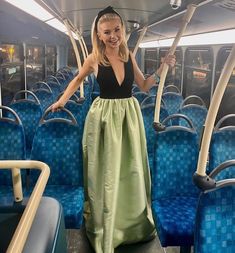 a woman in a long dress standing on a bus