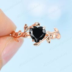 a woman's hand holding an engagement ring with a heart shaped black stone