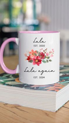 a pink and white coffee mug sitting on top of a book