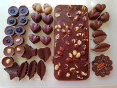 chocolates, nuts and blueberries are arranged on a plastic tray with leaves in the shape of hearts