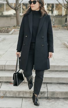 Woman in navy blue coat, black turtleneck, black jeans, black ankle boots which are classic shoes for fall, black leather bag walking down a set of steps Black Blazer With Jeans, Parisian Woman, Chic Black Outfits, Dress Like A Parisian, Navy Blue Coat