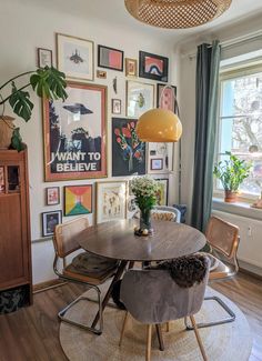 a dining room table with chairs and pictures on the wall in front of it's windows