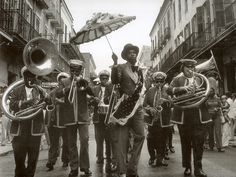 an old black and white photo of people marching down the street with musical instruments in their hands