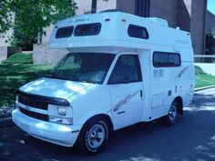 a white camper parked in front of a building on the side of a road