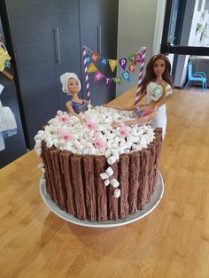 a barbie doll holding a cake with marshmallows on it