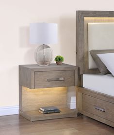 a night stand with a lamp on it next to a bed