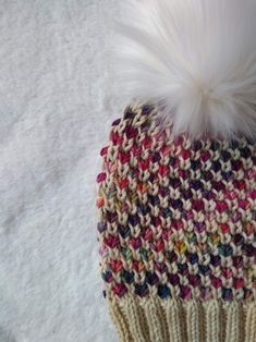 a knitted hat with a white fur pom - pom sitting on top of it