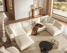 a large white sectional couch sitting on top of a living room floor next to a window