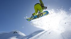 a man flying through the air while riding a snowboard on top of a snowy hill