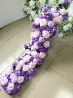 purple and white flowers are arranged in the shape of a letter on a tile floor