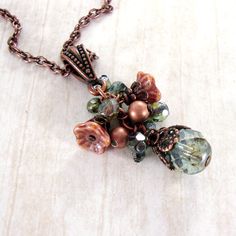 "A dainty cluster of Czech glass beads in shades of soft, subdued green and dusty pink. I adorned the larger beads and flowers with exquisitely detailed antiqued copper filigree to enhance the Old-World feel. The pendant hangs from antiqued genuine copper and features an adjustable lobster claw closure. --------------------------------------------------------------------------------------------- Dimensions and details: - Drop of the pendant (from top of the bail to bottom of bead drop) measures Pink Nature, Mixed Media Jewelry, Nature Necklace, Repurposed Jewelry, Long Necklaces, Assemblage Jewelry, Vintage Style Jewellery, Jewellery Ideas, Chic Jewelry