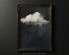 a black and white painting hanging on the wall next to a wooden frame with an image of a cloud floating in it